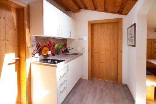 a kitchen with white cabinets and a wooden door at Chalet Stubai inklusive Stubai Super Card in Fulpmes