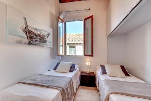 two beds in a room with a window at Botteri Palace Apartments in Venice