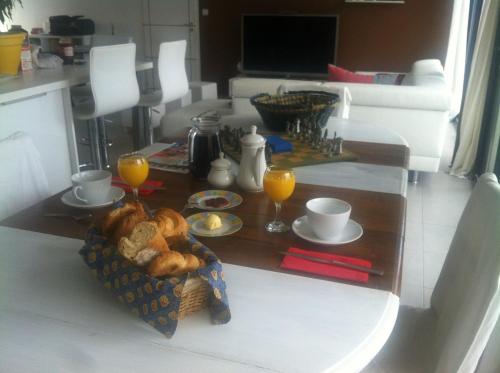 a table with a basket of bread and two glasses of orange juice at Villa Des Romieux in Pinet