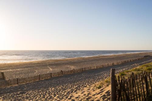 a beach with a fence and the ocean at JO&JOE Hossegor in Hossegor