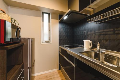 a small kitchen with a sink and a microwave at Trip Base HAKATAEKIMAE in Fukuoka