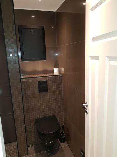 baño con aseo y TV en la pared en Apartment near the airport with ocean view, en Tromsø