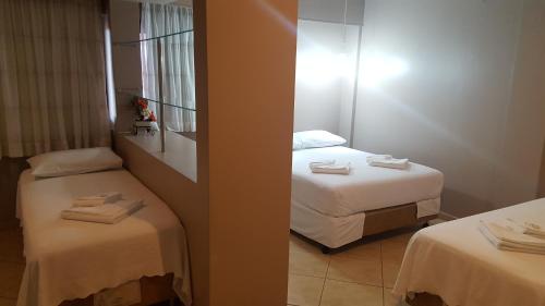 a hotel room with two beds and a mirror at Hotel Peroza Corbelia in Corbélia