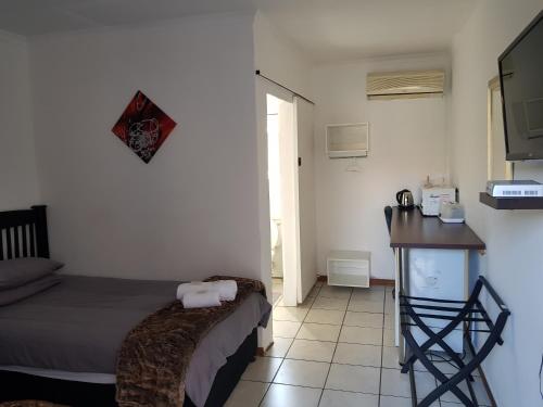 a bedroom with a bed and a table and a counter at Kgosi Lodge in Kimberley