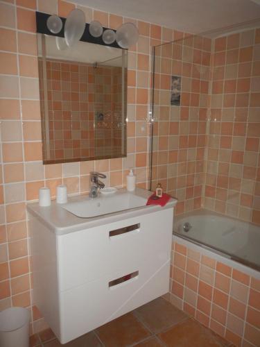 a bathroom with a sink and a mirror and a tub at Au bon accueil in Fayence