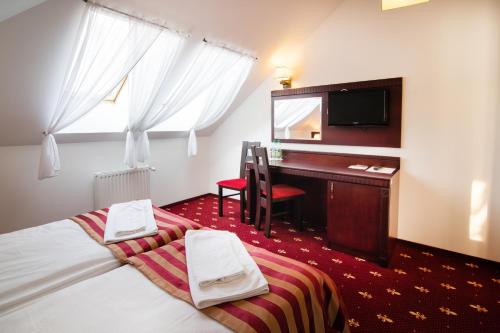 a hotel room with two beds and a desk in it at Hotel Platinum Hrubieszów in Hrubieszów