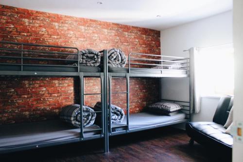 a room with three bunk beds against a brick wall at Taff Trail Bunkhouse in Merthyr Tydfil