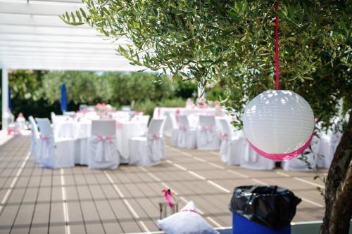 a bunch of white tables and chairs with a ball hanging from a tree at Agriturismo La Molara in Sessa Aurunca