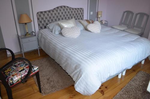 une chambre avec un grand lit avec des draps et des oreillers blancs dans l'établissement Les Treillettes, à Puylaurens