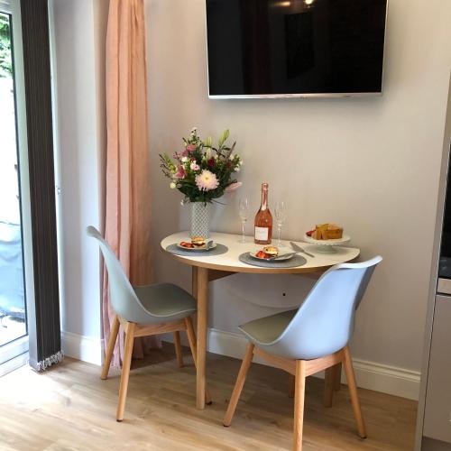 a table with a vase of flowers and a bottle of wine at Rivers Rest in Norwich