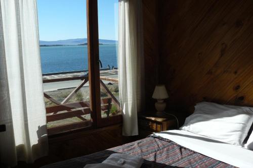 1 dormitorio con cama y vistas al océano en Cabañas Bahía Marina en El Calafate