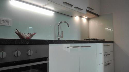 eine Küche mit weißen Schränken und einem Waschbecken in der Unterkunft Apartment Osk in Osijek