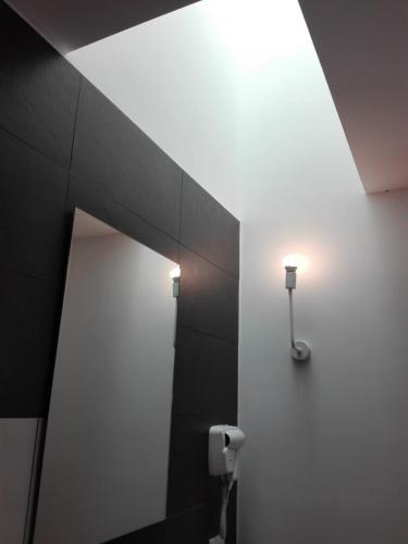 a bathroom with a mirror and a light on the wall at Patio 101 "Exclusive" in San Vito lo Capo