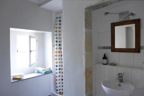 a bathroom with a sink and a mirror and a window at Le ciel par-dessus le toit in Salavas