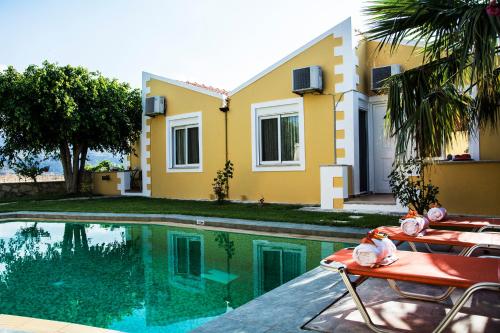 a villa with a swimming pool in front of a house at Plakalona Apartments in Exopoli