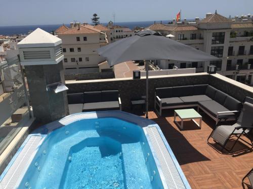 a swimming pool on top of a building with an umbrella at Hostal Boutique Doña Carmen - Adults Recommended in Nerja