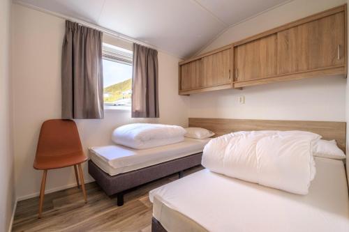 een kamer met 2 bedden en een stoel. bij Seaside cabin Skarsvåg in Skarsvåg