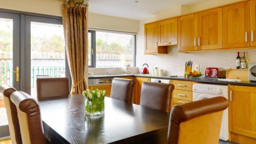 a kitchen with a wooden table and chairs and a table at Great Southern Killarney Holiday Homes in Killarney