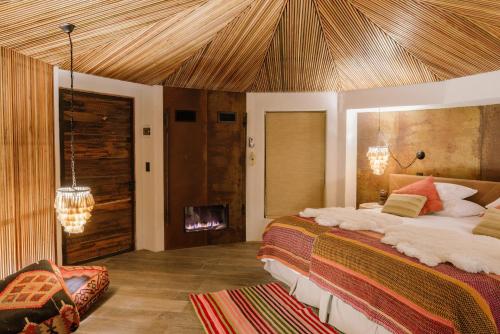 um quarto com uma cama grande e uma lareira em Hotel Desertica em San Pedro de Atacama