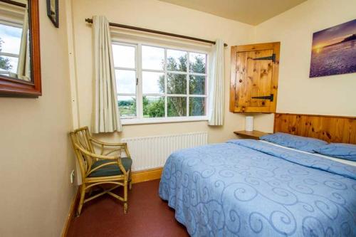 een slaapkamer met een bed, een stoel en een raam bij Rainbow hostel in Dingle