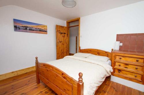 1 dormitorio con cama de madera y tocador de madera en Rainbow hostel, en Dingle