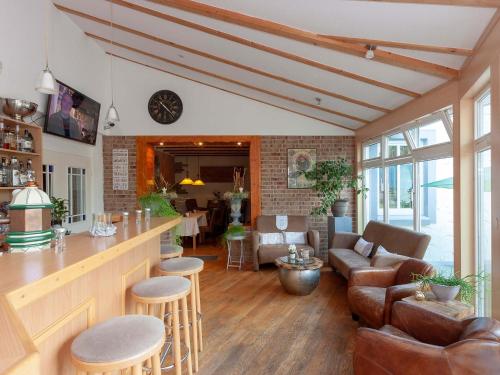 a living room with a bar with a couch and chairs at Hotel Herrlichkeit Dornum Janßen in Dornum