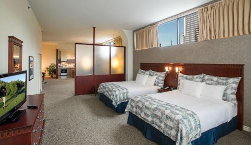 a hotel room with two beds and a flat screen tv at Le Square Phillips Hôtel & Suites in Montréal