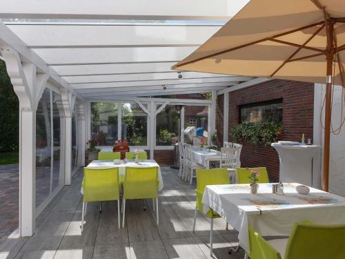 a patio with tables and chairs and an umbrella at Hotel Herrlichkeit Dornum Janßen in Dornum
