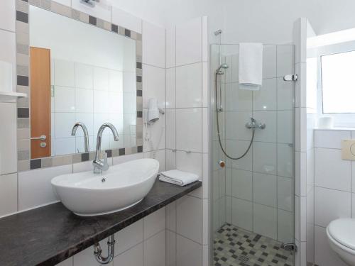 y baño blanco con lavabo y ducha. en Hotel Herrlichkeit Dornum Janßen, en Dornum