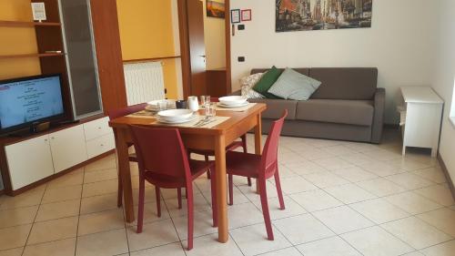 a dining room table with red chairs and a couch at Residenza Teodolinda in Monza