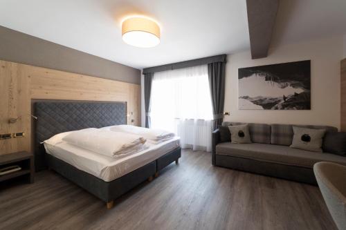 マルガ・チアペラにあるHotel & Ristorante Baita Dovichのベッドルーム(ベッド1台、ソファ付)
