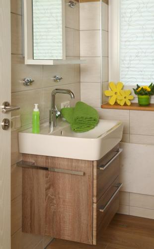 a bathroom sink with a green towel on it at Ferienhäuser May in Weigenheim
