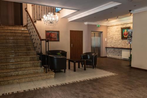 a lobby with stairs and chairs and a chandelier at Prima in Puławy