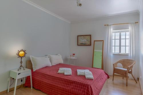 アルブフェイラにあるFLH Muralhas da Vila Apartmentのベッドルーム1室(赤い毛布と椅子付きのベッド1台付)