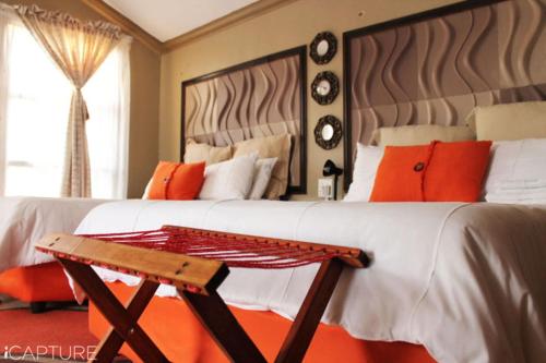 a bedroom with two beds with orange and white pillows at Vicky B Bed and Breakfast in Mogwase