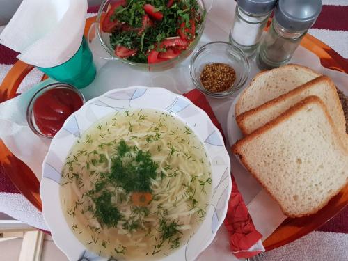 a table with a bowl of soup and a plate of bread at Klever-ok in Nerubayskoye