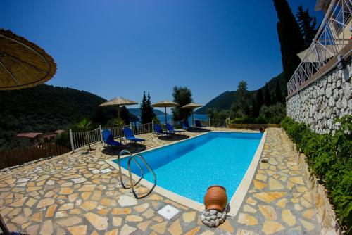 a swimming pool with chairs and umbrellas next to a building at Filoxenia in Yenion
