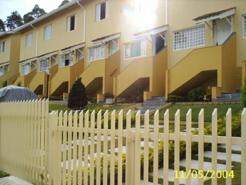 a white picket fence in front of a yellow building at Residencia Pereira in Serra Negra