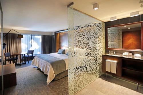 a hotel room with a bed and a glass wall at Hotel Cumbres Lastarria in Santiago