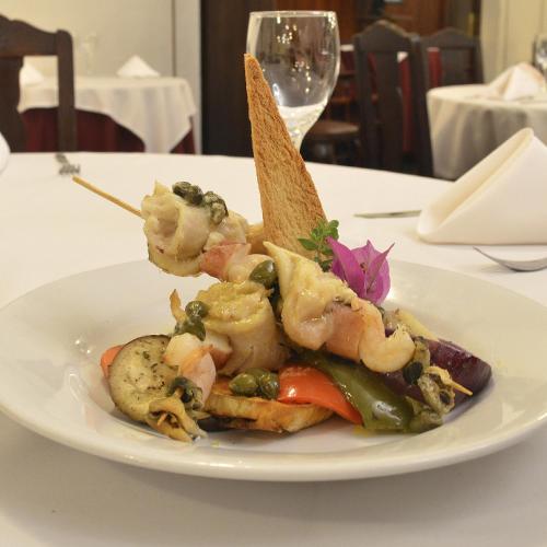 a plate of food with shrimp and vegetables on a table at Argentino Hotel Casino & Resort in Piriápolis