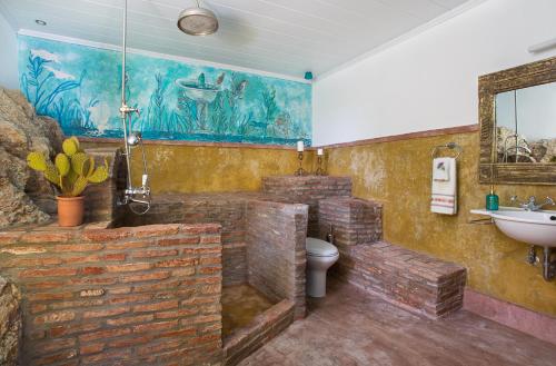 baño con paredes de ladrillo, lavabo y aseo en Archontikon House, en Perlengiánika