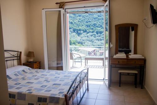 a bedroom with a bed and a desk and a balcony at Filoxenia in Yenion