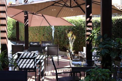 a patio with tables and chairs and an umbrella at Bergerie du Château - Lacapelle Marival in Lacapelle-Marival