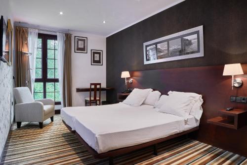 une chambre avec un grand lit blanc et une chaise dans l'établissement Hotel Granda, à Cangas de Onís
