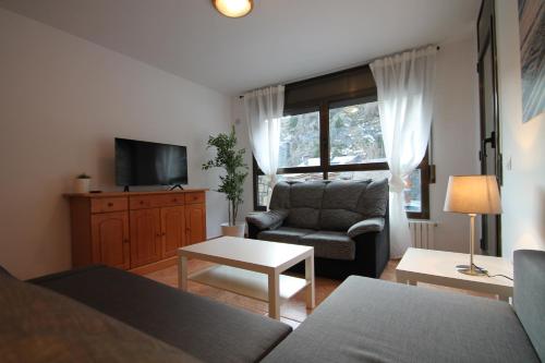 een woonkamer met een fauteuil en een televisie bij Pont de Toneta 1,1 Ransol, Zona Grandvalira in Ransol