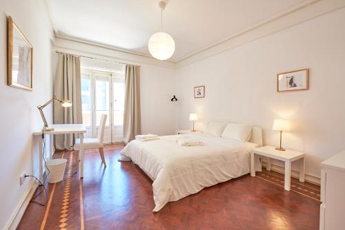 una camera bianca con un grande letto e una scrivania di Campo Pequeno Prestige a Lisbona