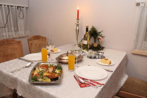 a dining table with a plate of food and a candle at Viesu nams AMRAI in Ventspils