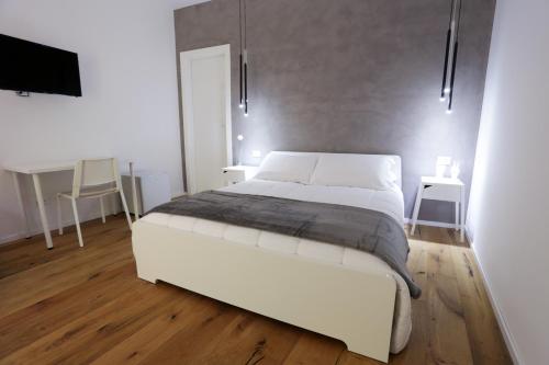 a bedroom with a large white bed and a desk at Reusuite in Ragusa