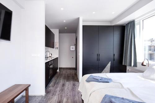a bedroom with a white bed and a kitchen at Svala Apartments by Heimaleiga in Reykjavík