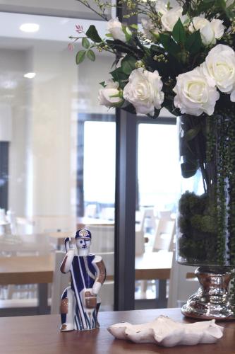 a vase with white roses and a figurine on a table at HOTEL ARZÚA in Arzúa
